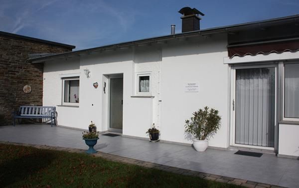 Ein weißes Haus mit einer blauen Bank davor