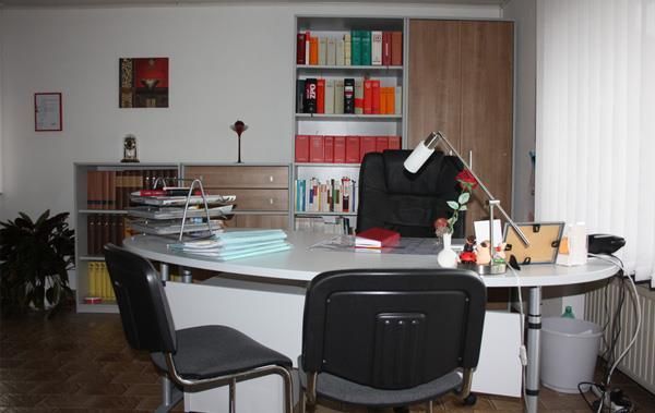 Ein Schreibtisch mit zwei Stühlen und einer Lampe in einem Zimmer