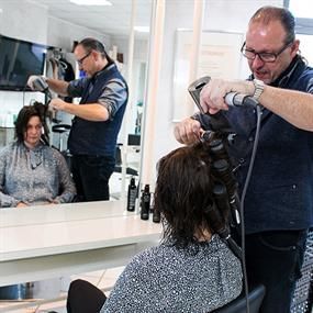 Ein Mann föhnt einer Frau in einem Salon die Haare.