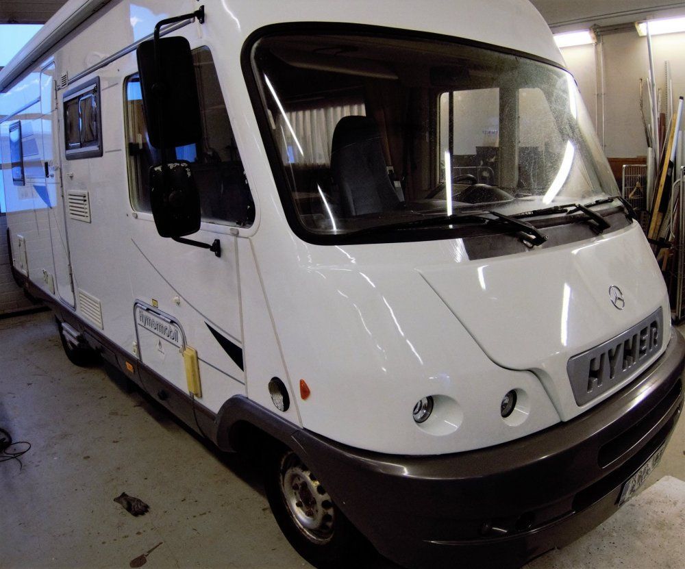 Valkoinen Hymer-matkailuauto pysäköitynä sisätiloihin, näkymä vasemmalta edestä