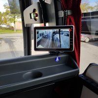 Bussin sisustus, jossa pieni näyttö näyttää käytävän ja näkymän ikkunasta