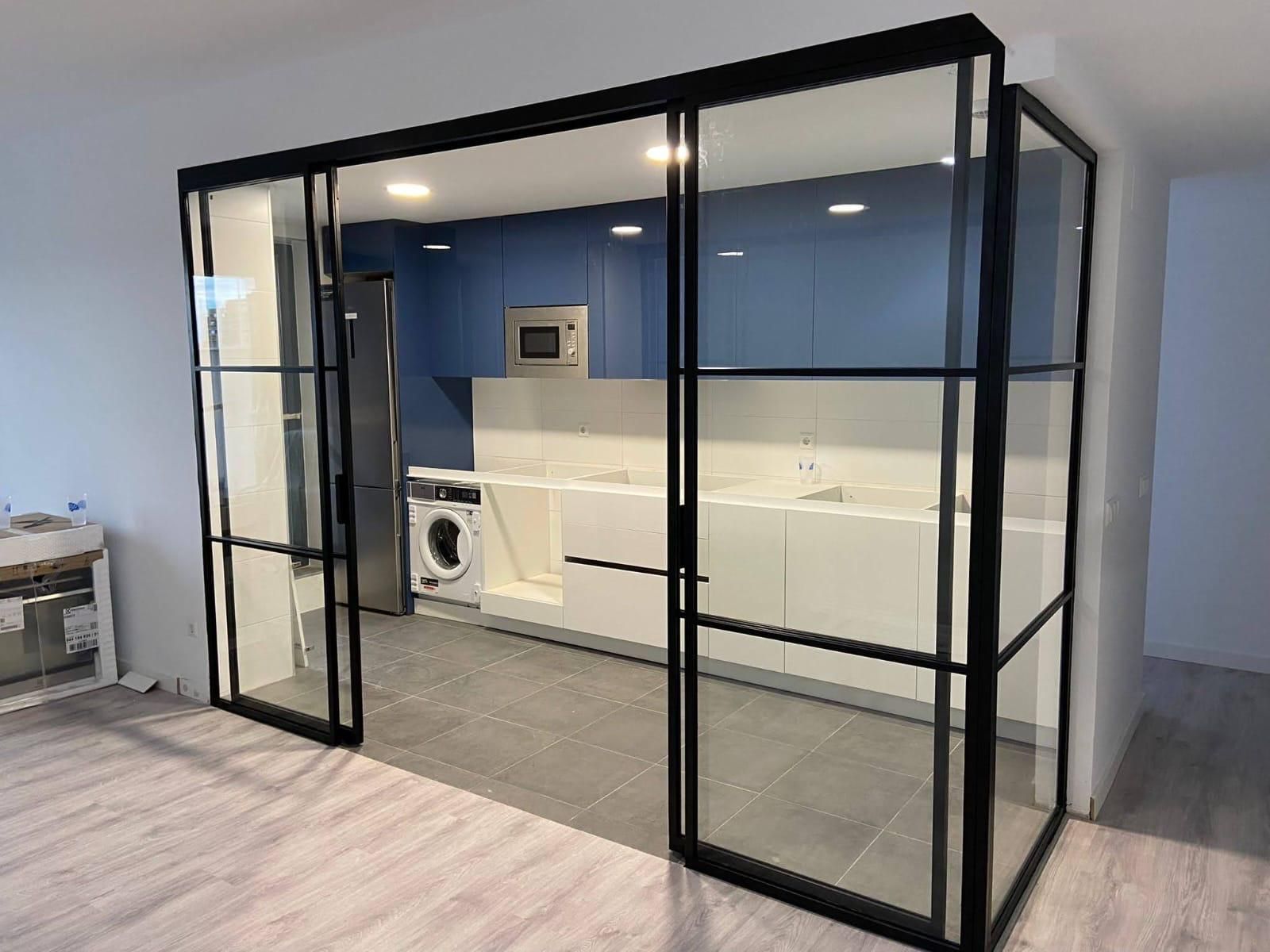 Moderno cuarto de lavado con paredes de cristal, armarios azules y electrodomésticos blancos