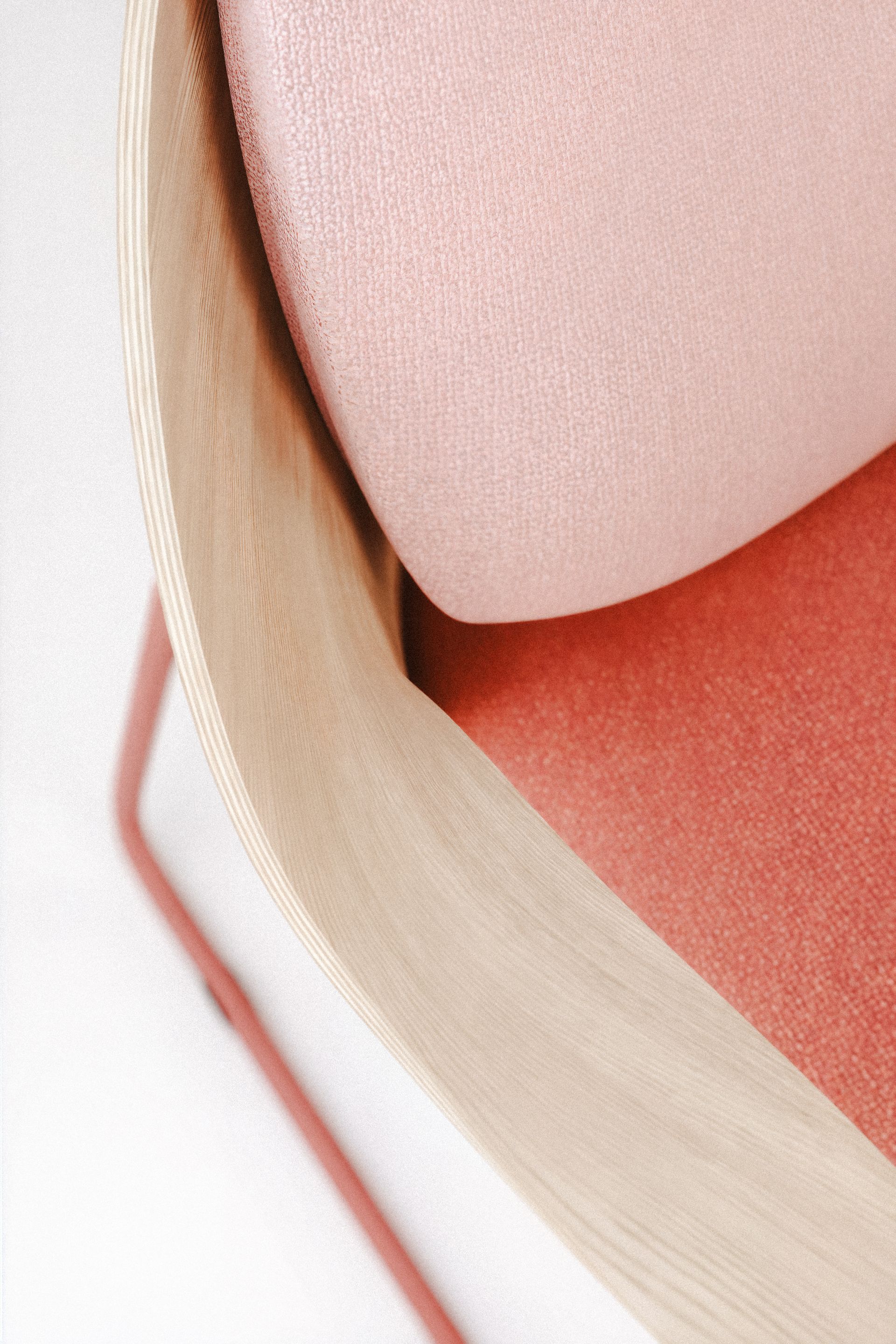 Nahaufnahme eines rosa Polsterstuhls mit hellem Holzrahmen und rosa Metallbeinen.