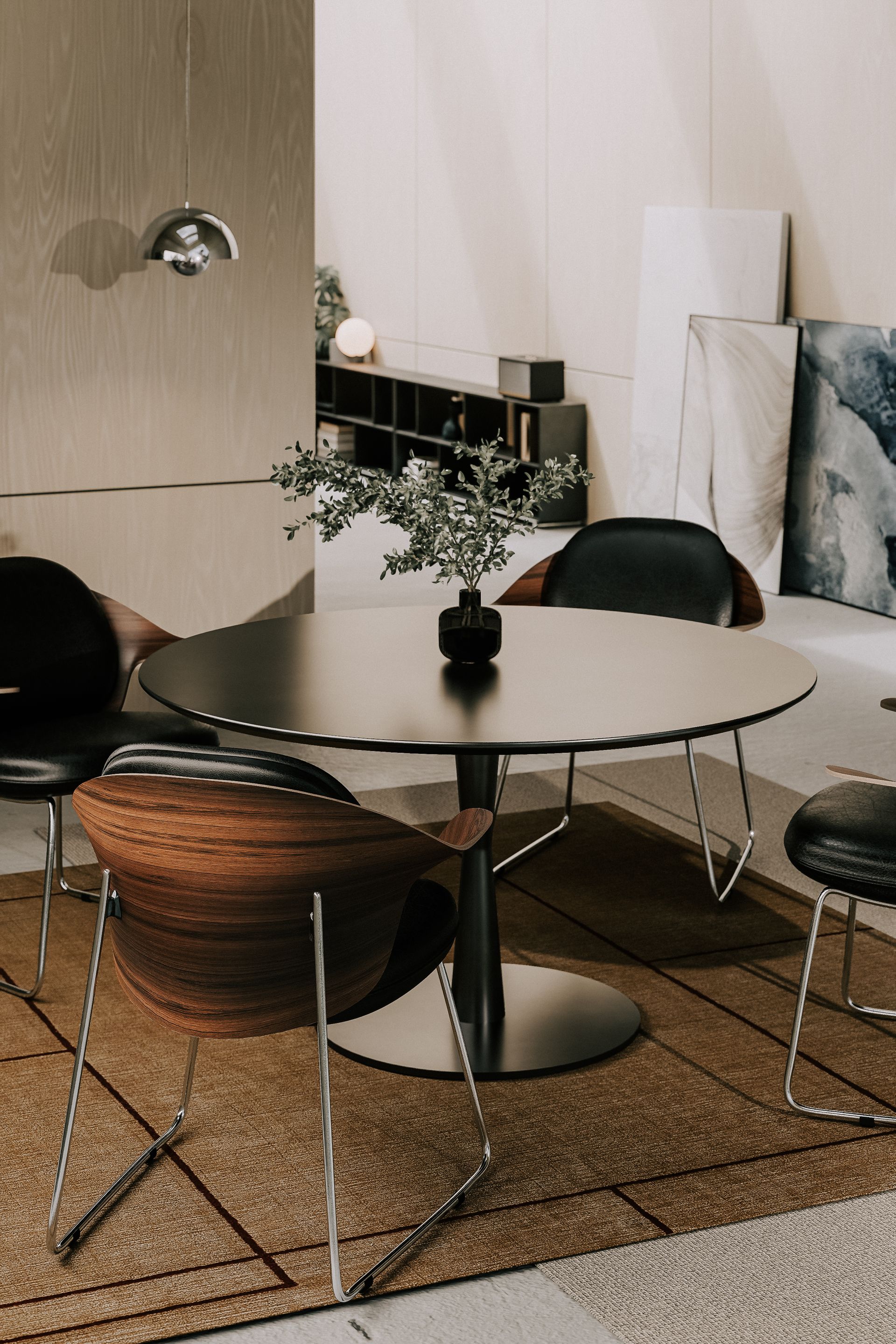 Esszimmer mit rundem Tisch, schwarzen Stühlen und Teppich. Vase mit Grünpflanzen. Neutrale Töne.