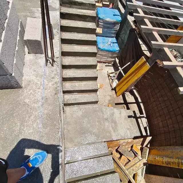 Escalera en construcción con escalones de hormigón, lonas azules, estructura de madera.