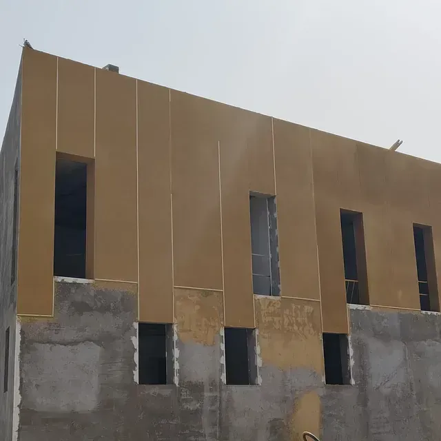 Edificio parcialmente terminado con paredes superiores de color beige y sección inferior de hormigón.