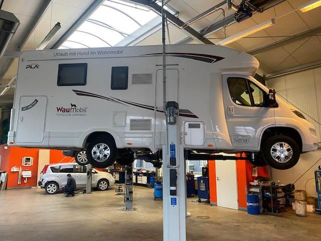 Ein Wohnmobil steht auf einer Hebebühne in einer Garage.