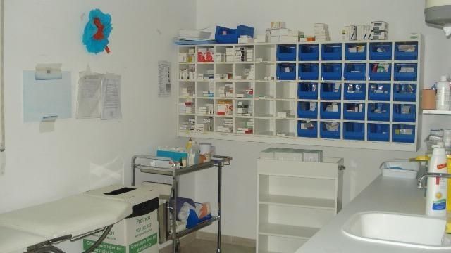 Habitación médica luminosa con estantes de suministros, una cama y un lavabo.