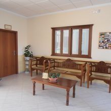 Luminoso salón con muebles de madera, una mesa de centro, sillas y una ventana en la pared.