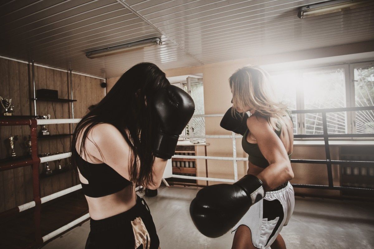 Dos mujeres boxeando en un ring, con guantes y ropa deportiva.