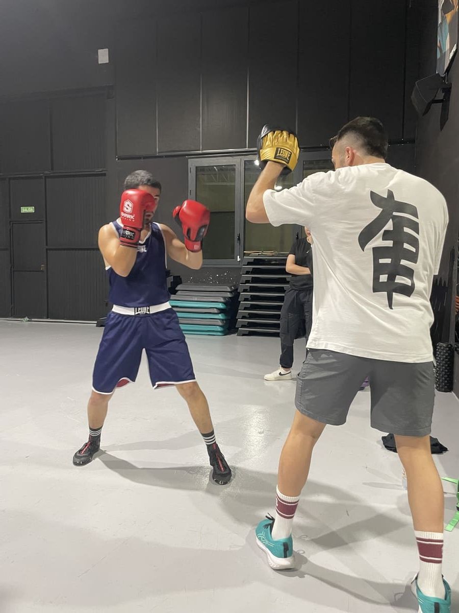 Dos mujeres boxeando en un ring, con guantes y ropa deportiva.
