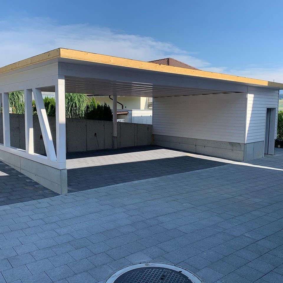 Ein weisser Carport mit Holzdach in einer Einfahrt. Foto von der Witschi Malerei.