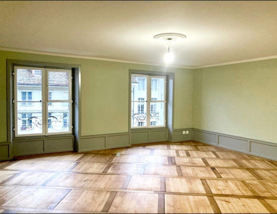 Ein leerer Raum mit Holzboden und grünen Wänden. Foto von der Witschi Malerei.