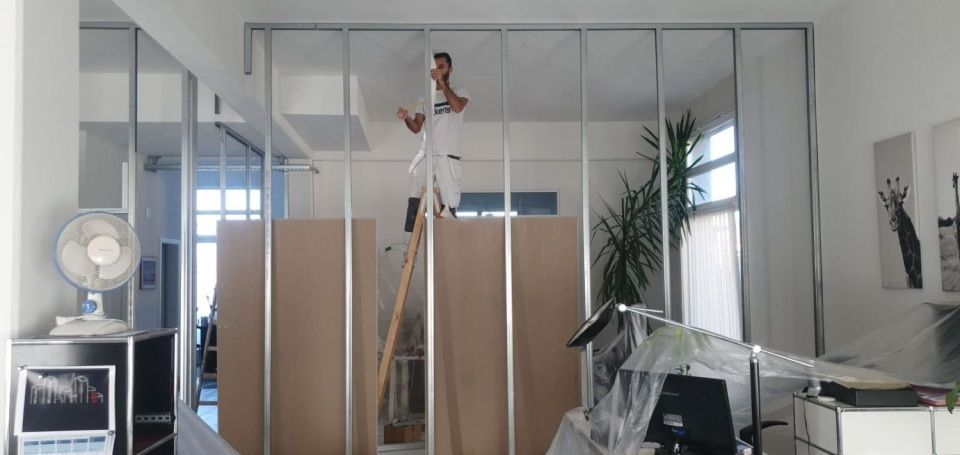 Ein Mann steht in einem Raum auf einer Leiter. Foto von der Witschi Malerei.