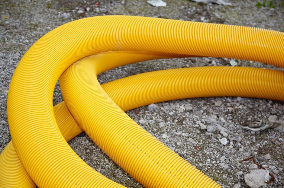 Tuberías de drenaje corrugadas amarillas sobre una superficie gris y pedregosa.