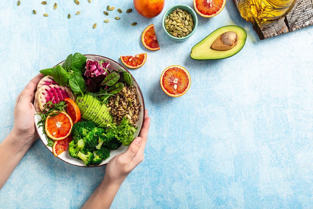 Una persona sostiene un recipiente con verduras y frutas.