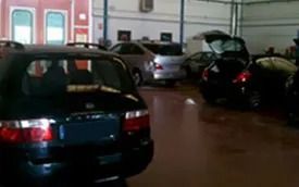 Varios coches aparcados en un aparcamiento cubierto, entre ellos un coche negro en primer plano.