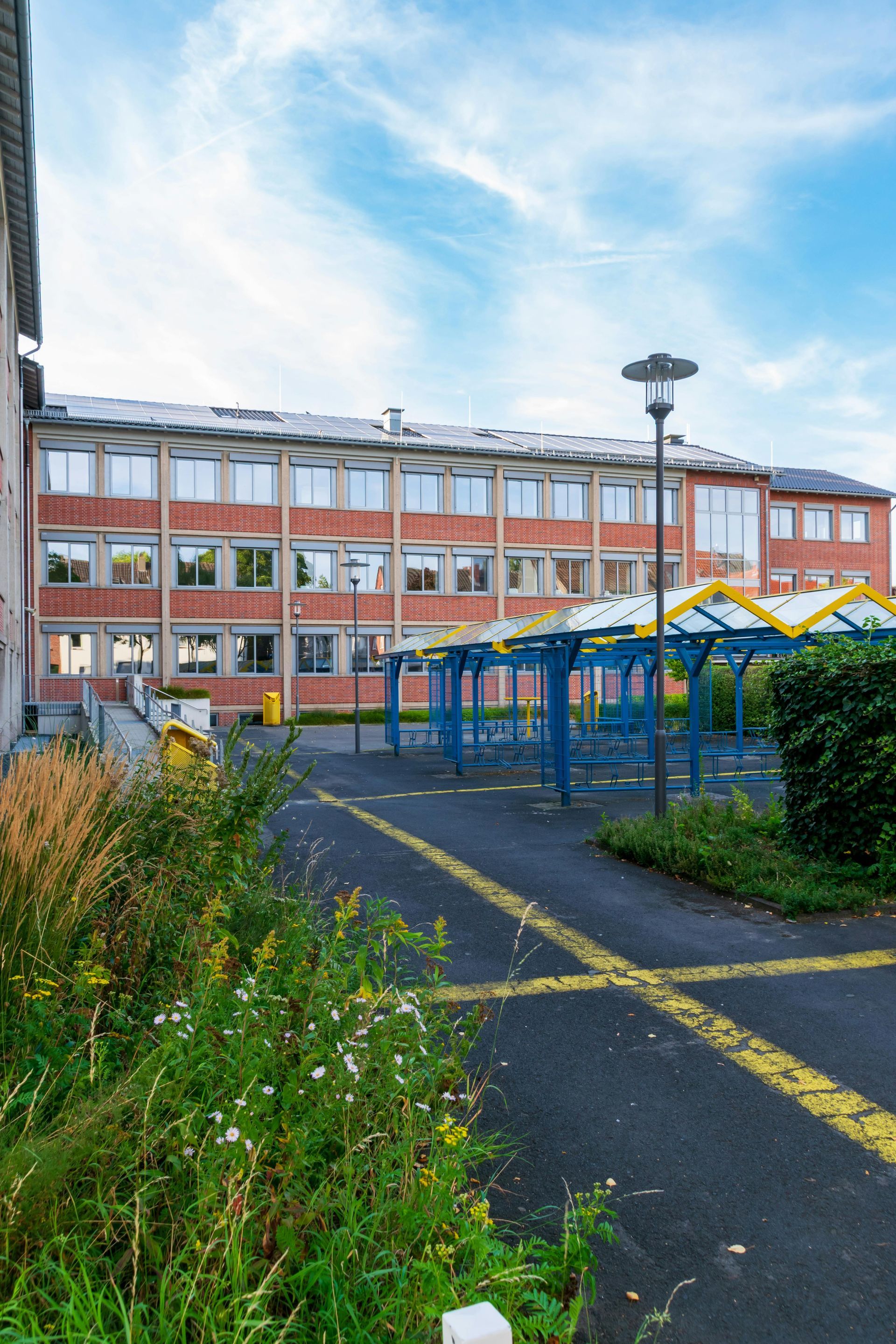 Ein Putzwagen mit Sprühflaschen und Tüchern steht in einem hellen Büroflur und wird von einem behandschuhten Arbeiter gehalten.