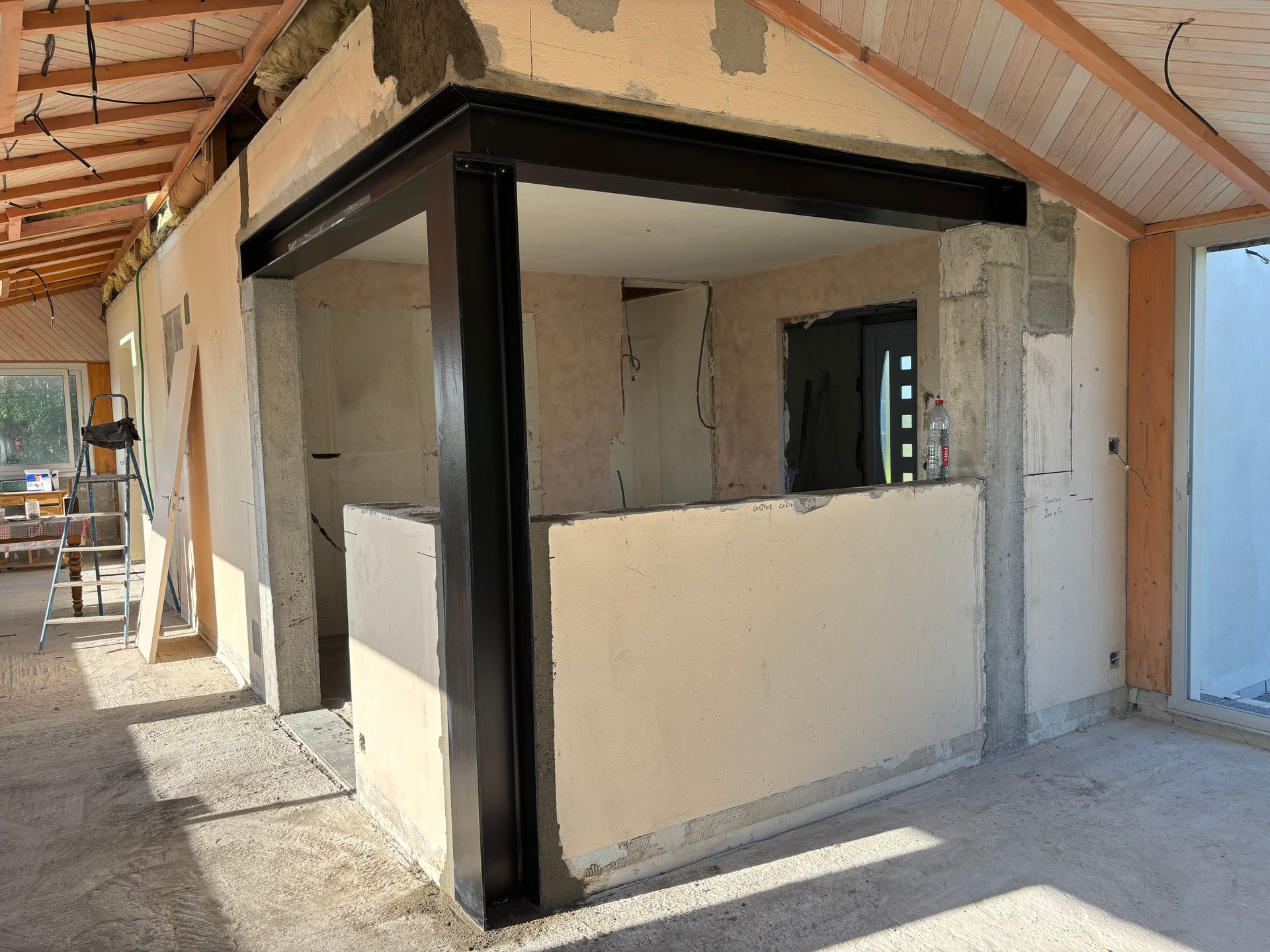 Petit kiosque ou stand inachevé à l'intérieur d'un passage couvert, avec des finitions noires et un muret à mi-hauteur.