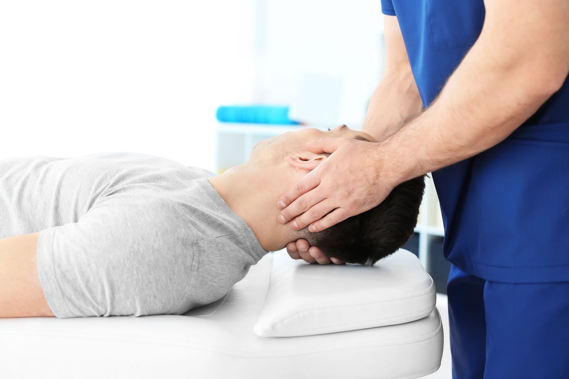 Chiropracteur ajustant le cou d'un patient ; le patient est allongé sur une table.