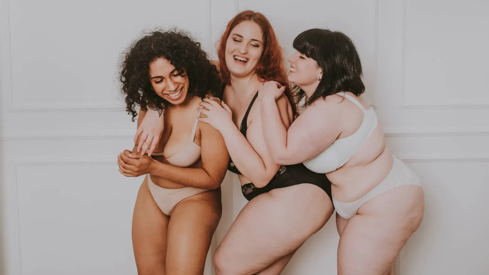 Manos organizando ropa en perchas; vestidos y suéteres de tonos neutros.