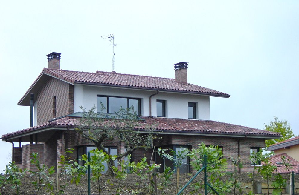 Una casa con techo de tejas rojas y una valla alrededor