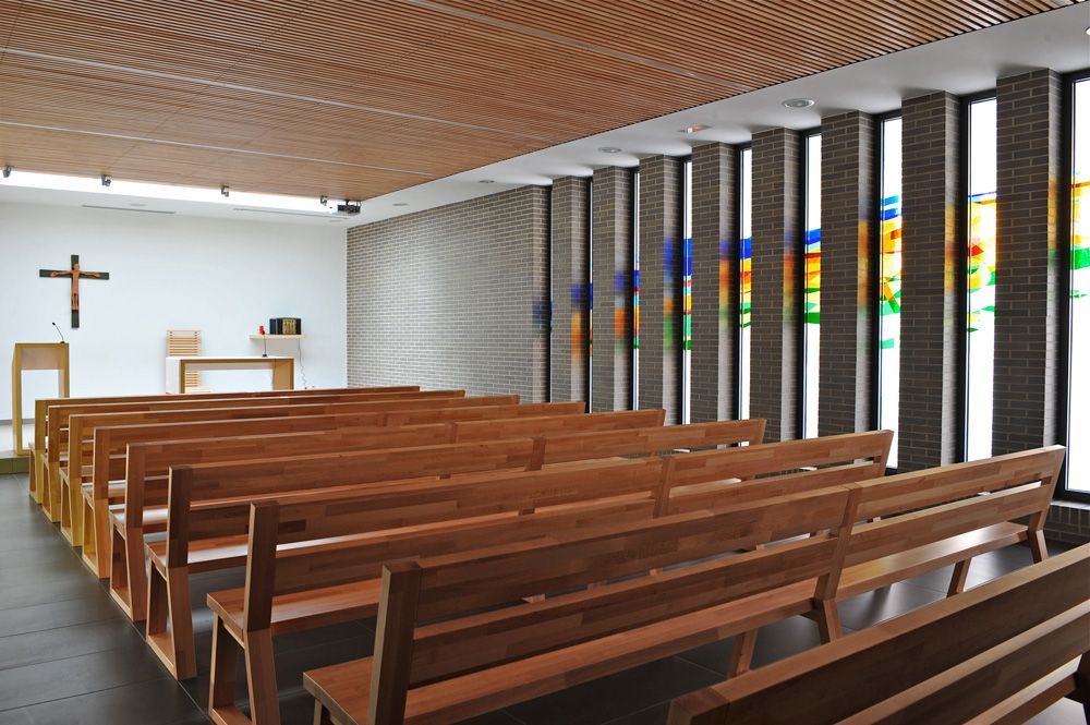 Filas de bancos de madera en una iglesia con vidrieras