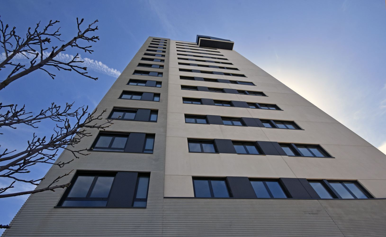 Mirando hacia arriba a un edificio alto con muchas ventanas