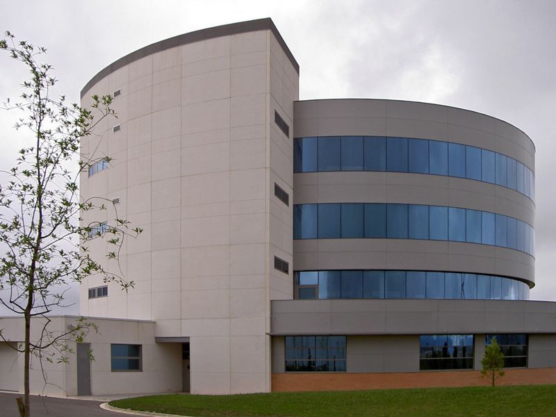 Un edificio con muchas ventanas y un árbol delante.