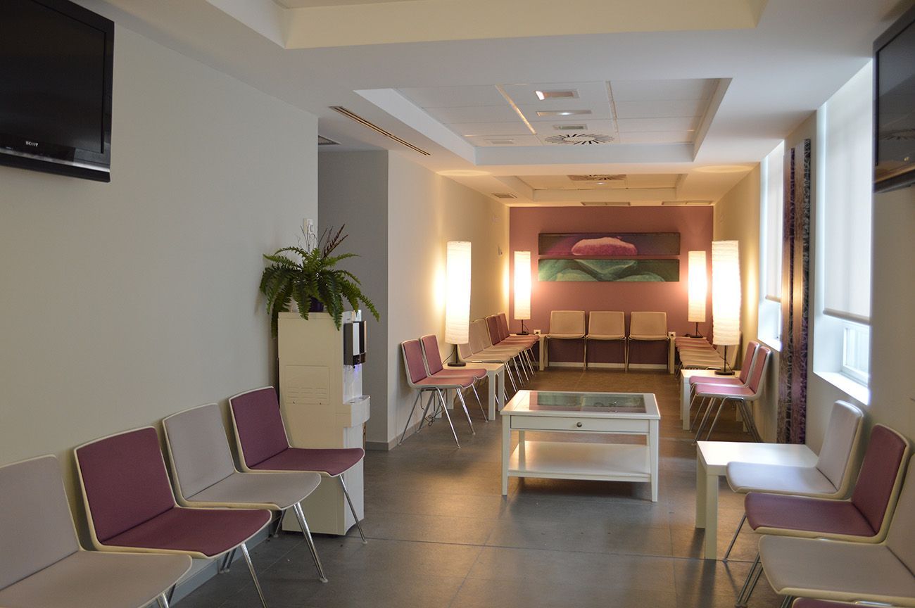 Una sala de espera con sillas moradas y un cuadro en la pared.