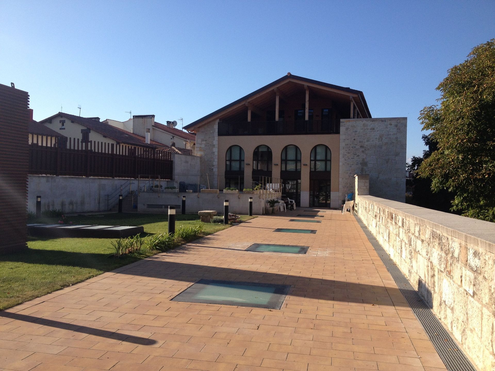 Una pasarela de ladrillos conduce a un gran edificio con ventanas arqueadas.