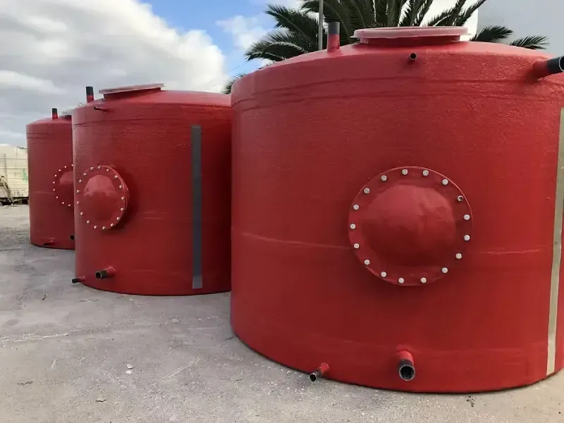 Grandes tanques cilíndricos de metal rojo al aire libre sobre una superficie de hormigón.