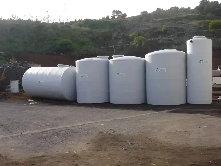 Varios grandes tanques y cilindros de almacenamiento blancos estaban alineados en un terreno de tierra