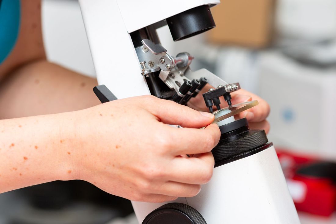 Mains ajustant un microscope blanc dans un environnement de laboratoire