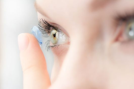 Gros plan sur une personne insérant une lentille de contact souple dans un œil noisette