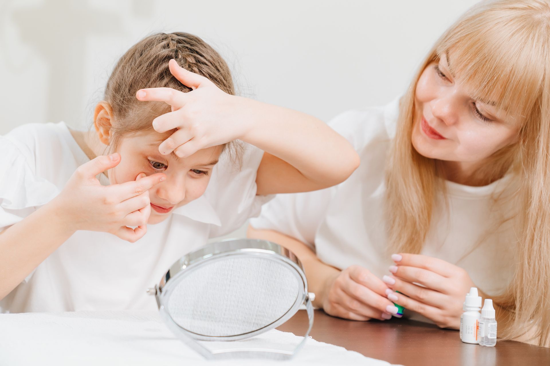 Une maman assiste un garçon avec un miroir pour mettre des lentilles de contact