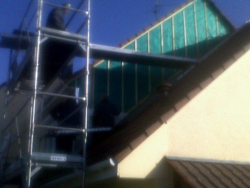 Échafaudage près du toit d'une maison. Des ouvriers, perchés sur l'échafaudage, semblent travailler sur la charpente en bois.