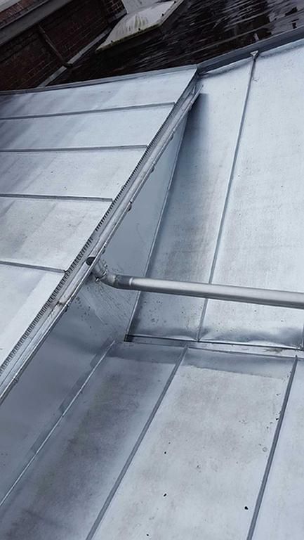 Toiture métallique avec panneaux inclinés et descente de gouttière.