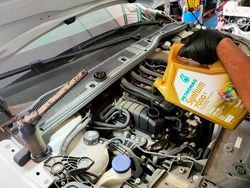 Una persona está vertiendo aceite en el motor de un automóvil.