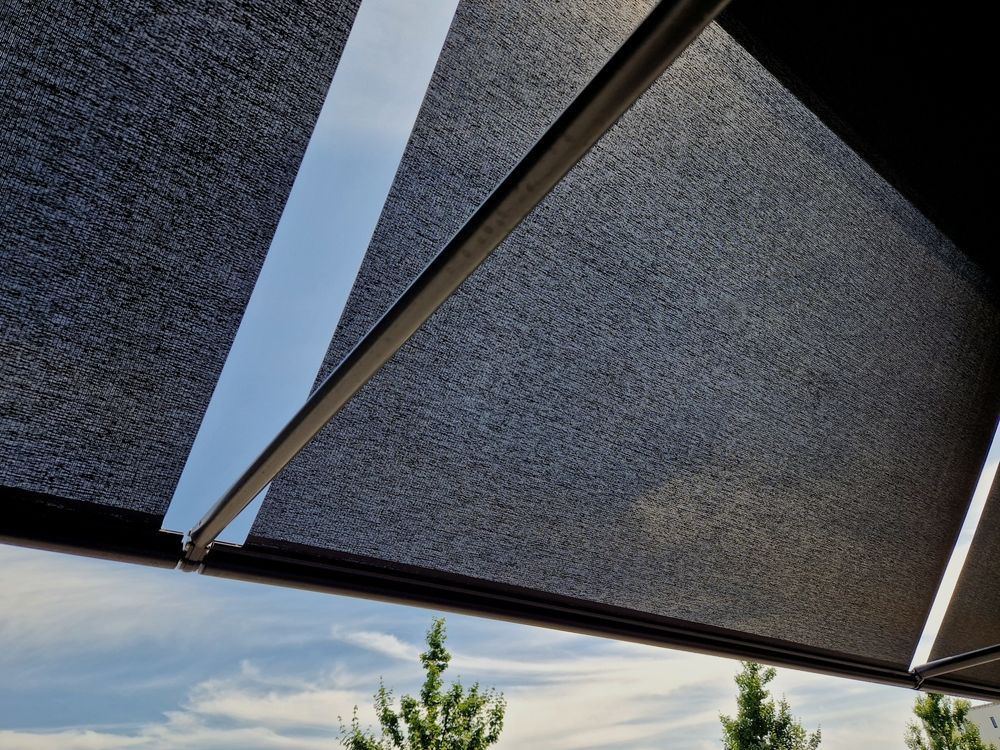 Toldos negros se extendían sobre nuestras cabezas, recortados contra un cielo azul con nubes sobre los árboles.