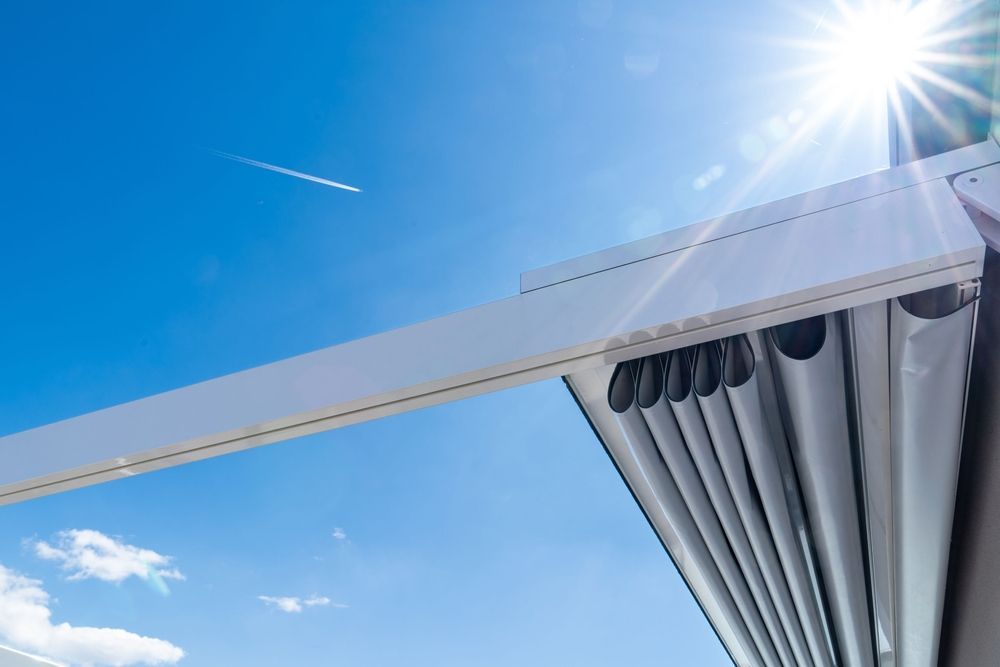 Edificio blanco moderno con techo inclinado contra un cielo azul brillante y un destello de sol.
