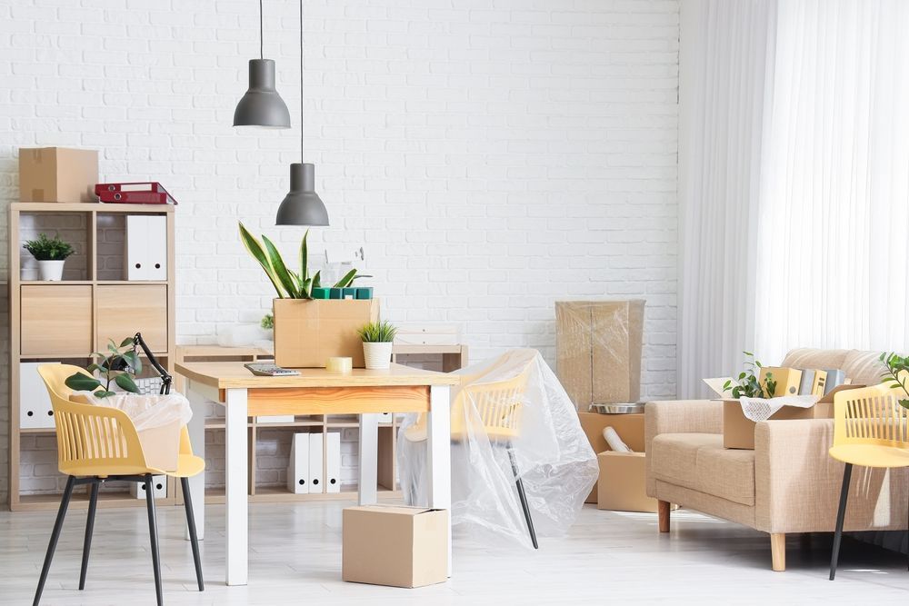Comedor moderno y luminoso con mesa de madera, sillas amarillas, lámparas colgantes y plantas en macetas.