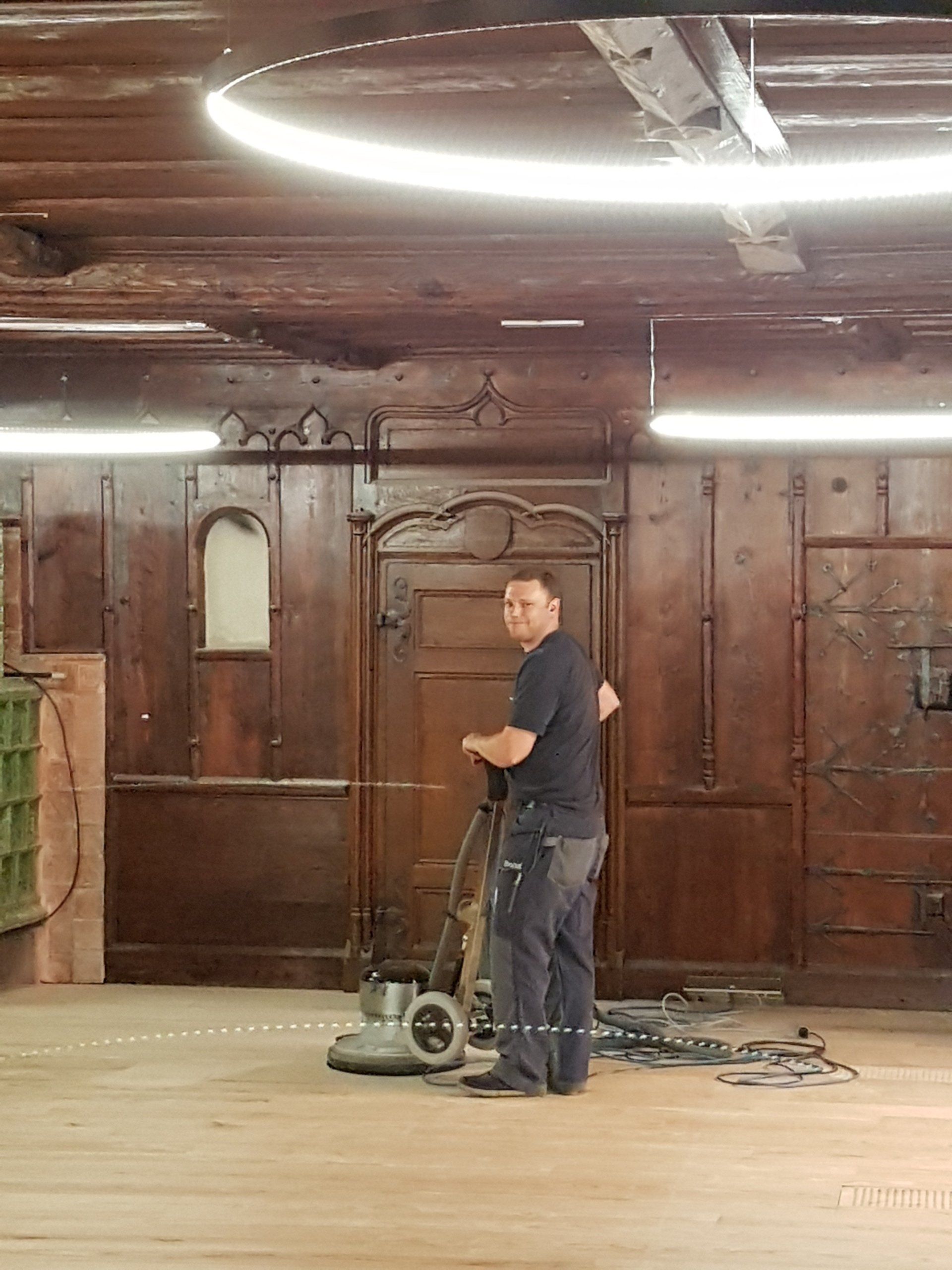 Une machine à poncer le bois à côté d'un homme qui regarde la caméra