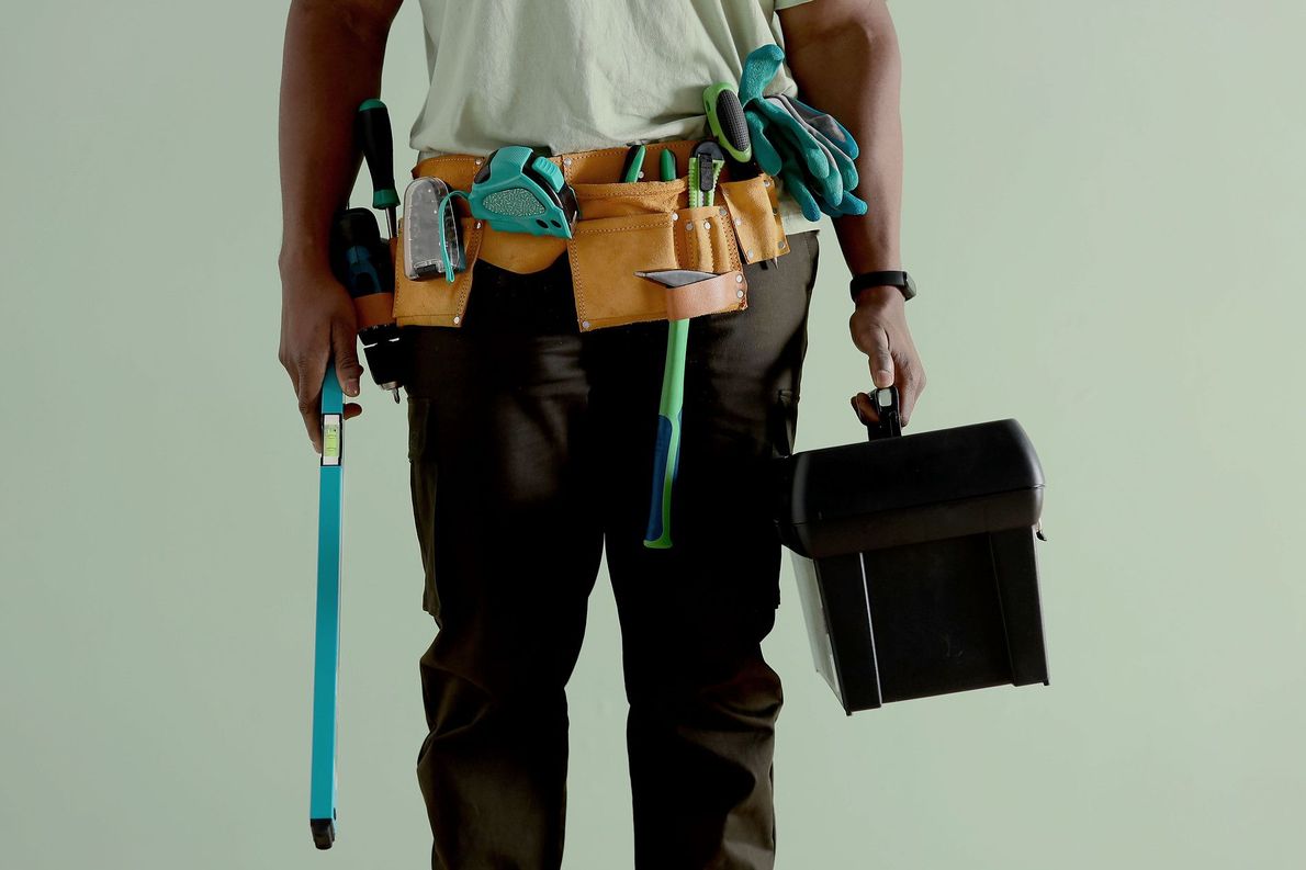 Photo d'un homme avec une ceinture avec des outils et une caisse à outils