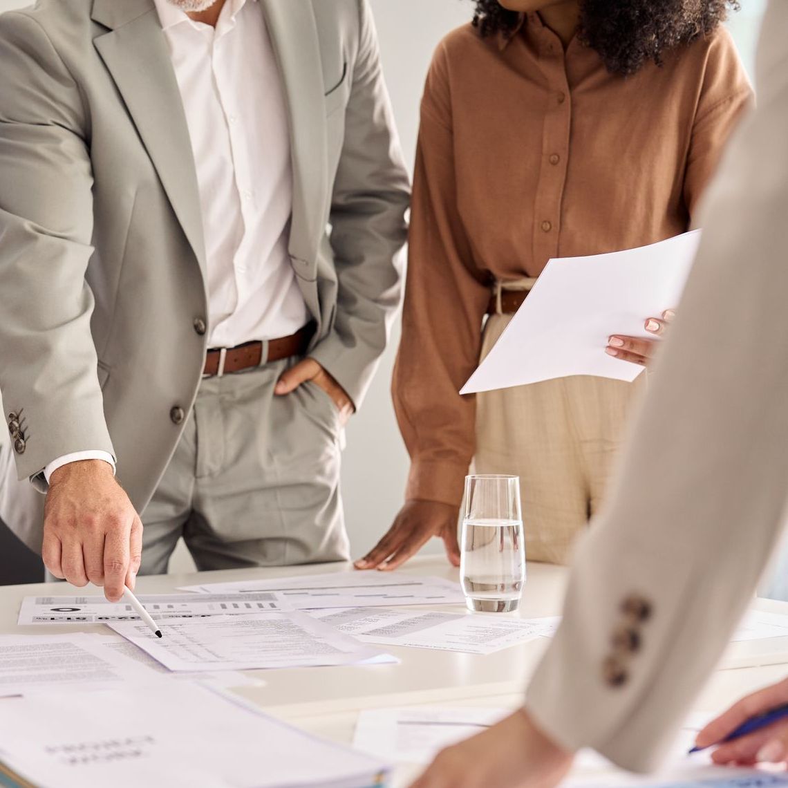 Un grupo de personas están sentadas alrededor de una mesa mirando papeles.