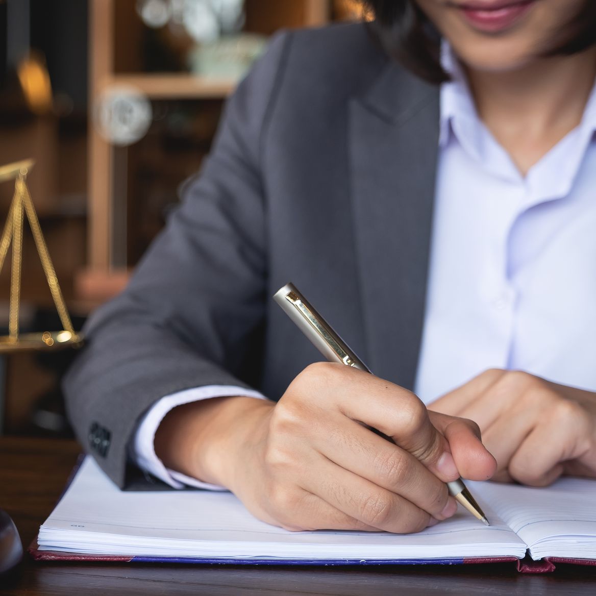 Una mujer está escribiendo en un cuaderno con un bolígrafo.