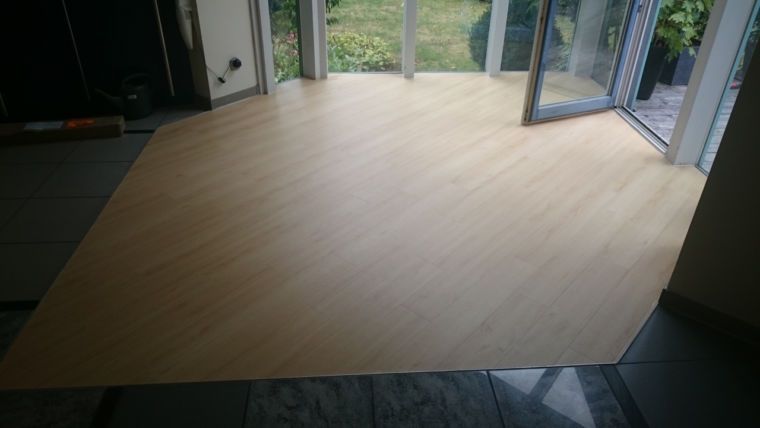 Hellfarbener Holzboden in einem Zimmer mit großen Glastüren, die auf eine Außenterrasse führen.