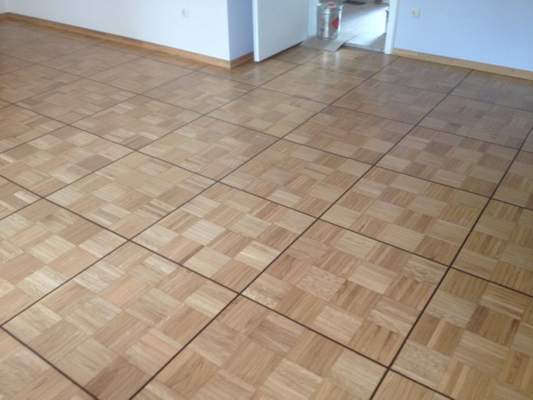 Ein Zimmer mit hellem, quadratischem Parkettboden in Schachbrettmuster.