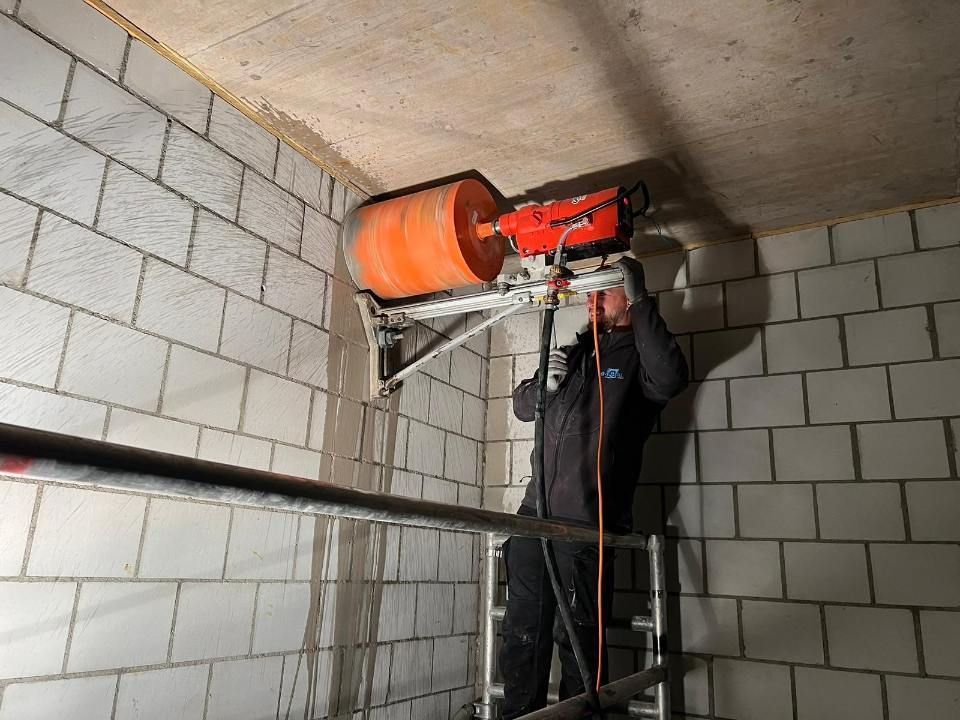 Mitarbeiter der SJ-TOTAL GMBH durchbohrt eine Wand