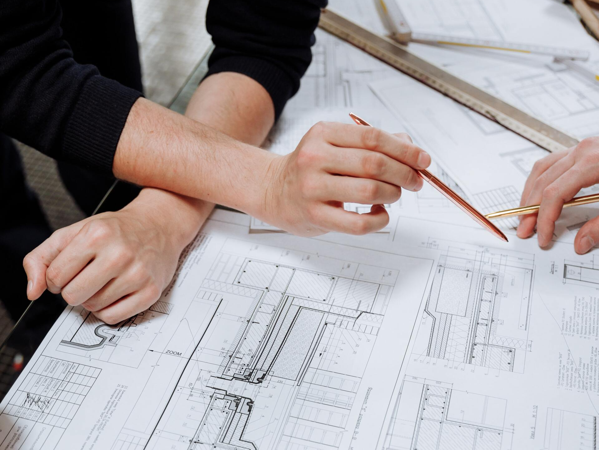 Deux personnes examinent des plans, pointant du doigt avec des crayons, sur un bureau.
